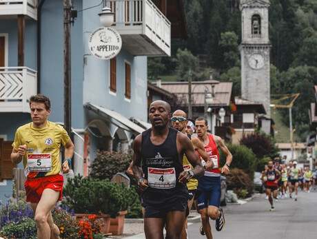 Group of runners racing through a mountain village with a church in the background.