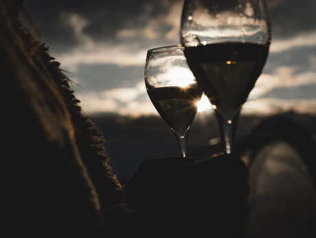 Two wine glasses at sunset with cloudy sky in the background