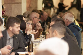 Long banquet tables under the portico of the cloister of the former Augustinian convent, filled with joyful people enjoying dinner and the company of friends.