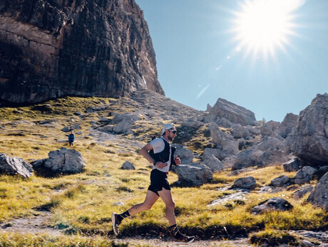The image shows an athlete from the Dolomiti di Brenta Trail with the Dolomites in the background
