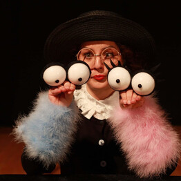 L'immagine mostra l'attrice durante lo spettacolo mentre utilizza due marionette