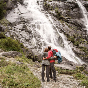 Couple trekking with stops to admire waterfall